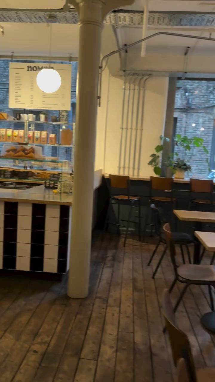 The black-and-white striped counter under globe pendant lights, the menu board and pastry cabinet behind